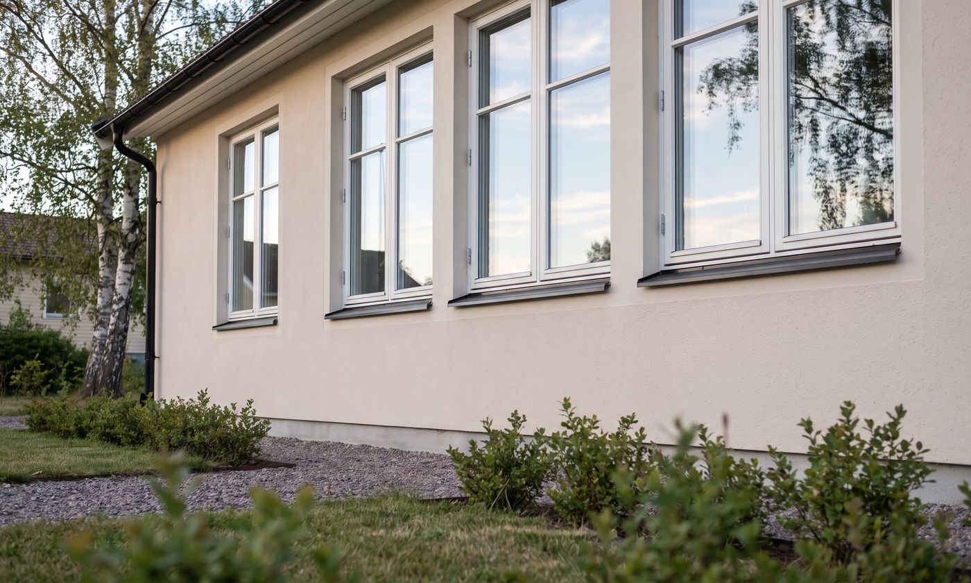 Nyputsade villafönster med vita karmar och fönsterbleck